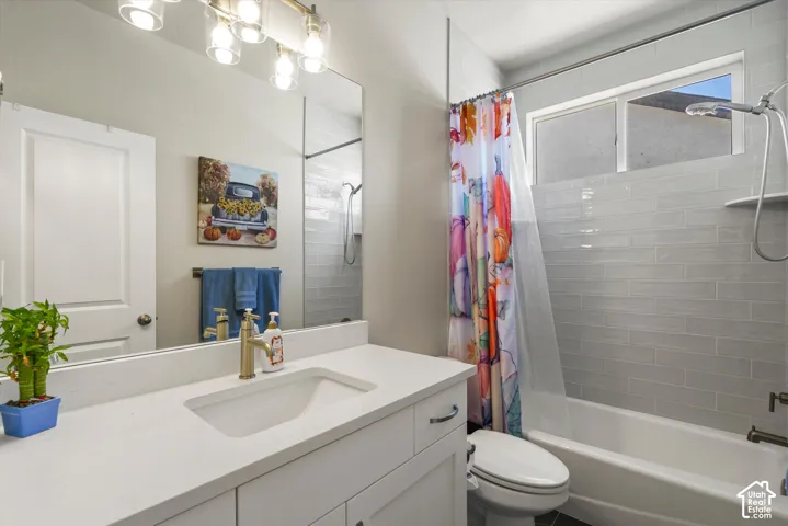 Bathroom featuring a white vanity with an integrated sink, polished countertop, and a contemporary light fixture