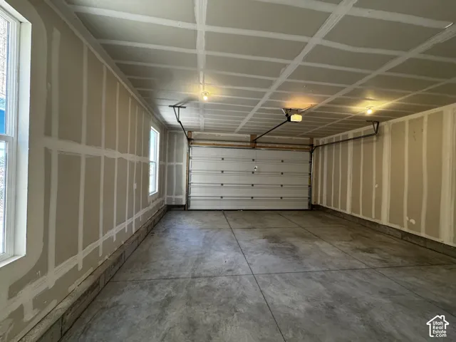 Spacious garage featuring a concrete floor, two windows, and an overhead garage door