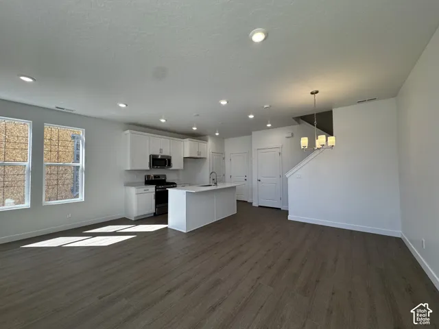 Open-concept living space featuring wood-finish flooring, recessed lighting, and a modern kitchen with white cabinetry