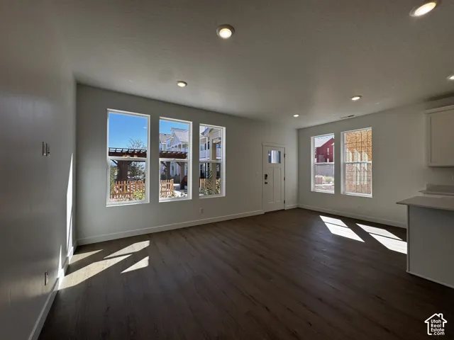 Wood-finish flooring, recessed lighting, multiple windows, white painted walls, and built-in cabinetry