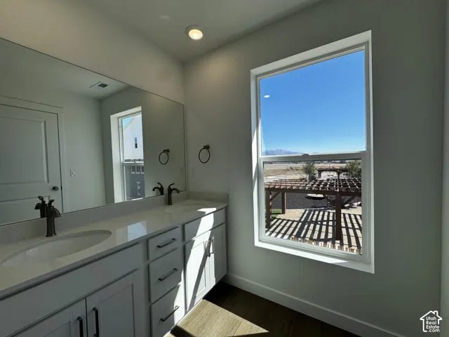 Dual vanity with undermount sinks, white cabinetry, and a large wall-mounted mirror