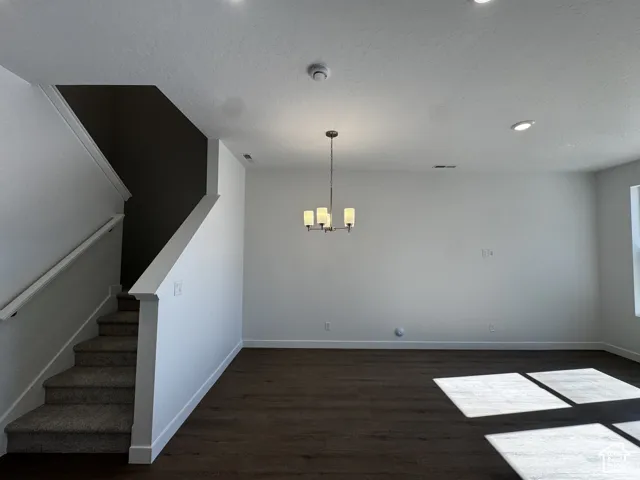 Recessed lighting, wood-finish flooring, chandelier, carpeted staircase, and an open layout