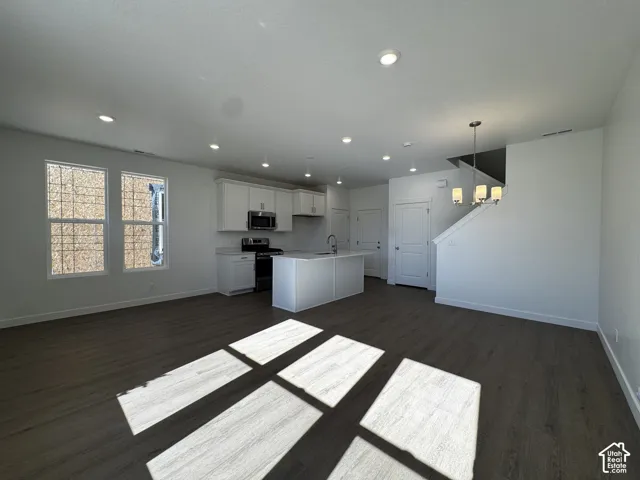 Open-concept living space with dark wood-finish flooring, recessed lighting, and a contemporary chandelier
