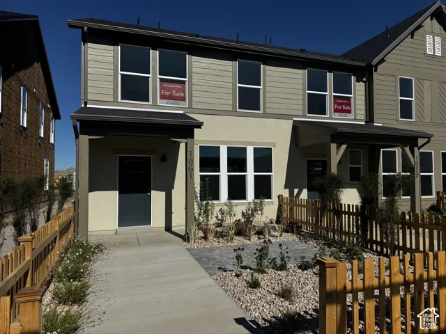 Stucco and siding exterior with dark trim accents, covered entry, front walkway, and low-maintenance landscaping