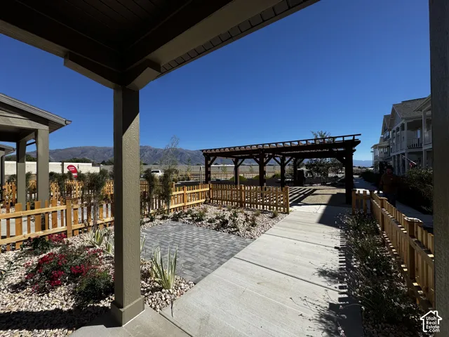 Covered patio entrance with a paver walkway leading to a wooden pergola
