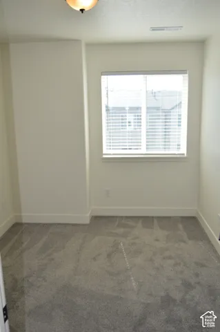 Neutral color palette with textured carpeting, a window featuring blinds, and a semi-flush mount ceiling fixture