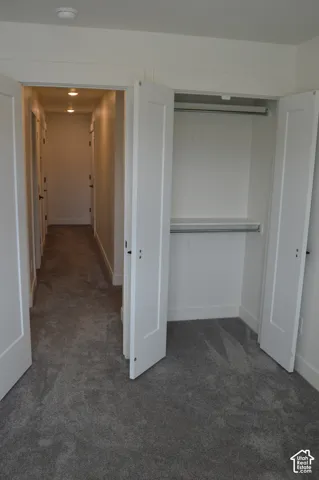 Recessed lighting illuminates the hallway, featuring solid core doors and gray carpeting