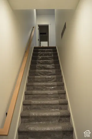 Carpeted staircase with wood handrail