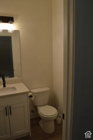 Vanity with a light-toned countertop, white cabinetry with dark hardware, and a wall-mounted light fixture