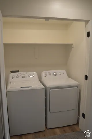 Appliance alcove with a built-in shelf, wood-finish flooring, and white washer and dryer units
