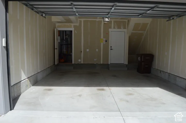 Spacious garage with concrete flooring, exposed ceiling joists, and two interior access doors