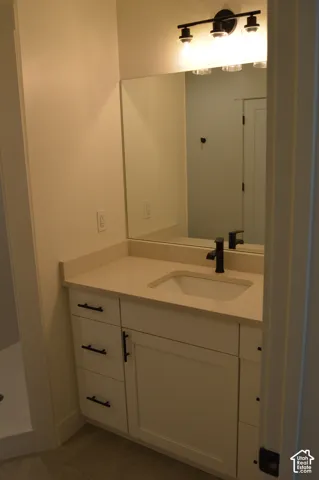 White vanity with dark hardware, a light-toned countertop, and an undermount sink