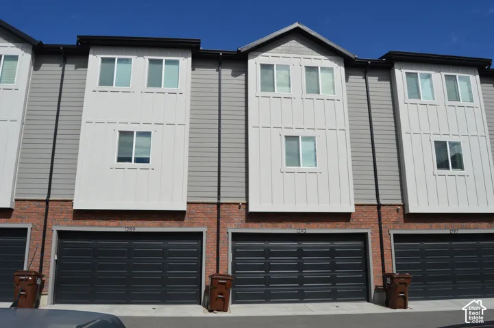 Contemporary exterior featuring brick and siding, multiple windows, and integrated garage doors