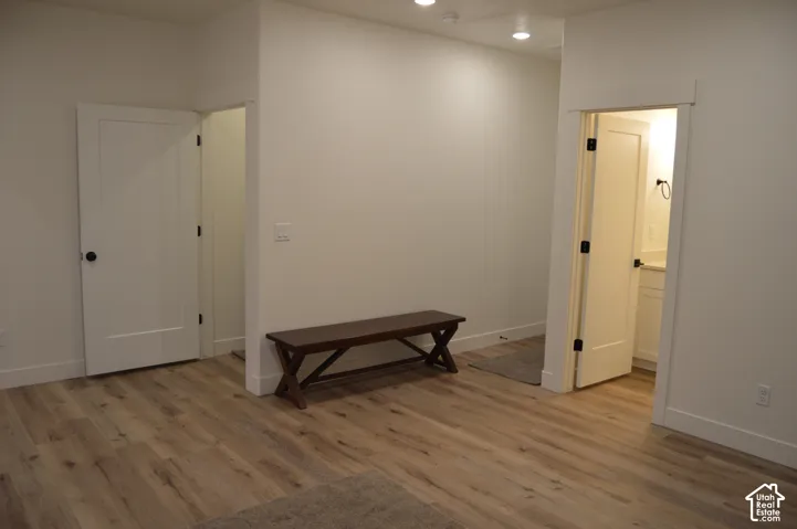 Wood-finish flooring throughout, bright white walls, recessed lighting, and white interior doors with dark hardware