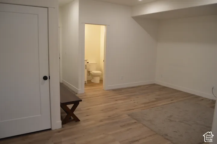 Wood-finish flooring throughout, white interior doors with black hardware, and bright white walls