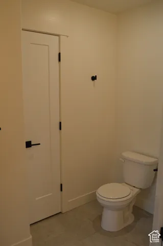 White interior door with black hardware, white walls, and gray tile flooring