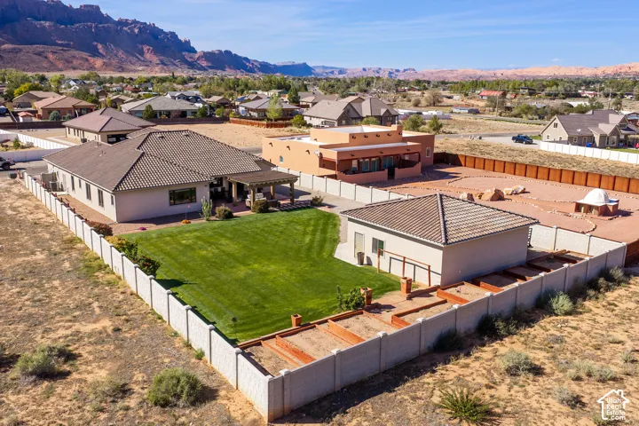 Tile roof residence with a fenced backyard, an expansive lawn, and a covered patio
