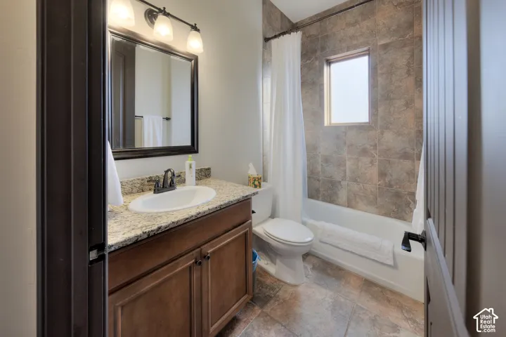 Vanity with a granite-style countertop, undermount sink, and wood-finish cabinetry