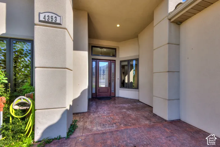 Recessed entry with a wood-panel door, sidelight windows, stamped concrete flooring, and stucco exterior