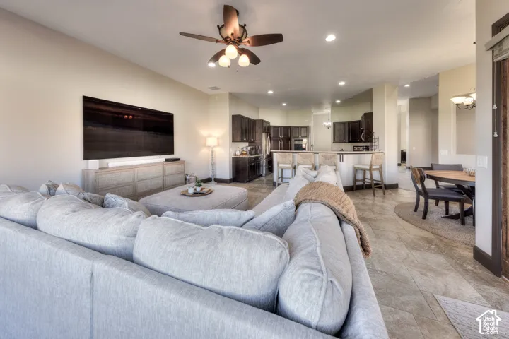 Recessed lighting, ceiling fan, wood-finish flooring, dark wood cabinetry, breakfast bar