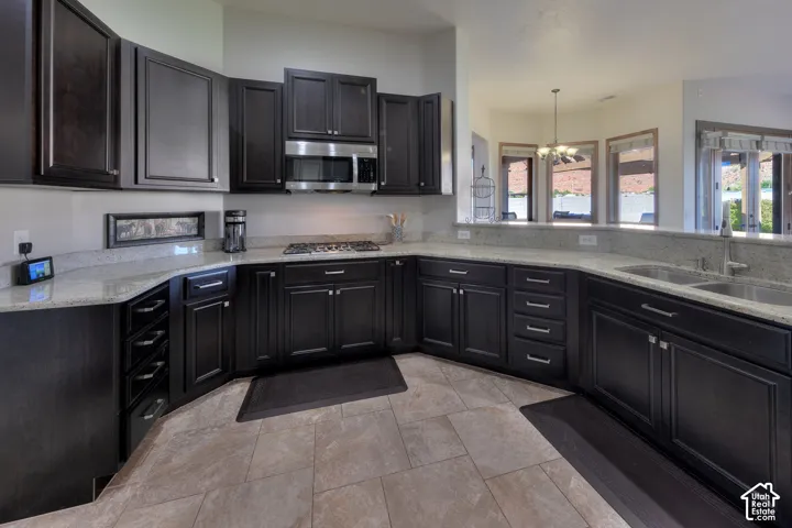 Kitchen featuring dark wood-finish cabinetry, light-toned countertops, and an undermount double basin sink