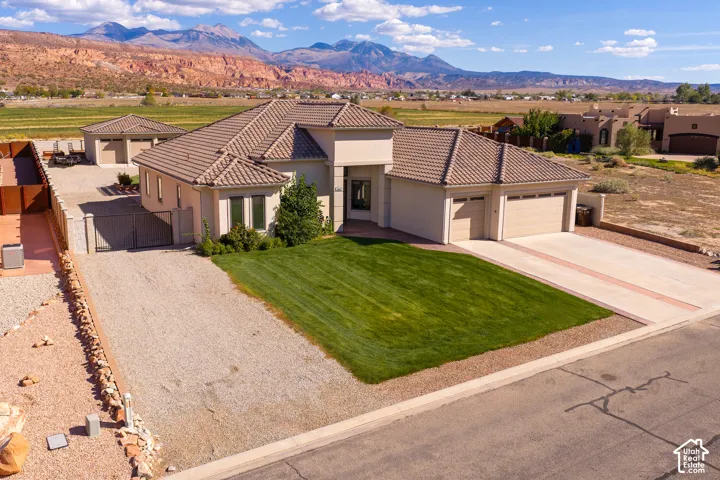 Stucco exterior with a tile roof, an integrated two-car garage, a detached two-car garage, and a gravel side yard