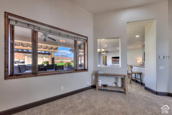 Wall-to-wall carpeting with dark wood-finish baseboards, an expansive window with wood-finish trim, and an architectural wall niche