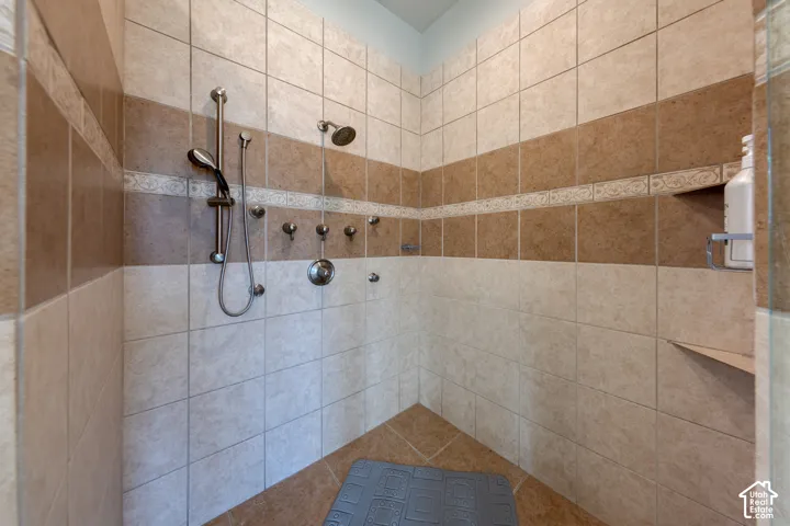 Fully tiled shower with contrasting tile band, built-in shelving, and dual shower heads