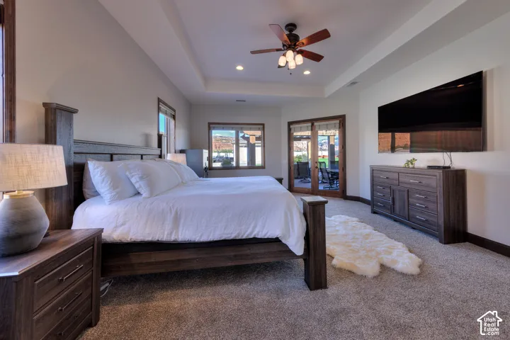 Tray ceiling with recessed lighting and a ceiling fan, plush carpet, and glass paneled doors