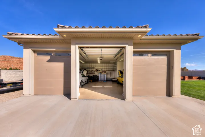 Three-bay garage with two tan sectional doors and one open bay, featuring a concrete driveway and tile roof
