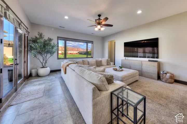 Spacious living area featuring a large picture window, ceiling fan with integrated lighting, recessed lighting, and a wall-mounted media console