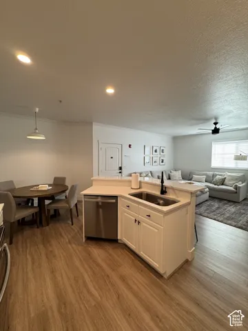 Open-concept living space featuring wood-finish flooring, recessed lighting, and a kitchen island with an undermount sink