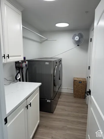 White shaker-style cabinetry with matte black hardware, white countertop, wood-finish flooring, and two recessed ceiling lights