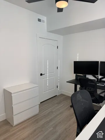 Wood-finish flooring with white baseboards and a white painted door featuring matte black hardware