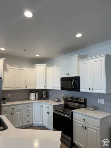 White shaker cabinetry with black hardware, complementing a gray tile backsplash and light-toned countertops