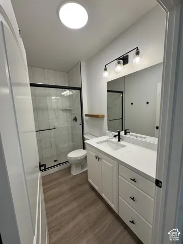 Wood-finish flooring, white vanity with black hardware, integrated sink, and white countertop
