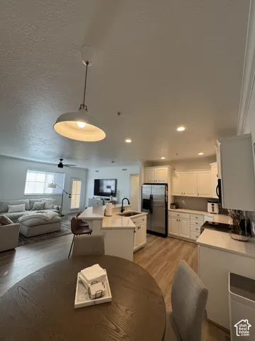 Open concept living space featuring wood-finish flooring, white cabinetry, stainless steel appliances, and recessed lighting