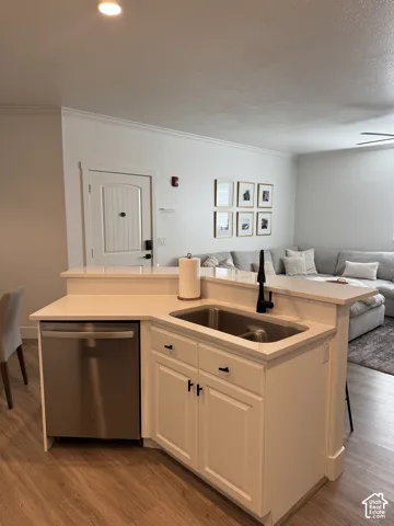 Kitchen island with white cabinetry, stainless steel sink, quartz countertops, and a built-in stainless steel dishwasher