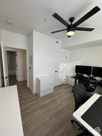 Wood-finish flooring throughout, modern ceiling fan with integrated lighting, solid core interior doors, white trim and baseboards, and a neutral wall color