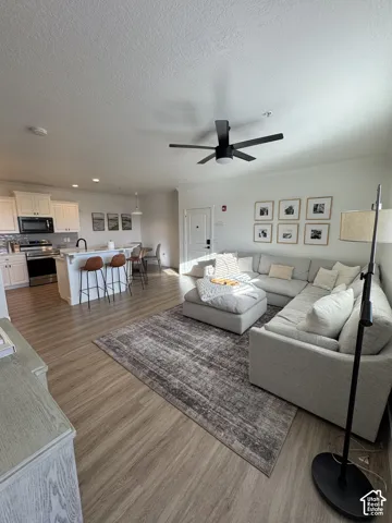 Open-concept living area featuring wood-finish flooring, a modern ceiling fan, and recessed lighting