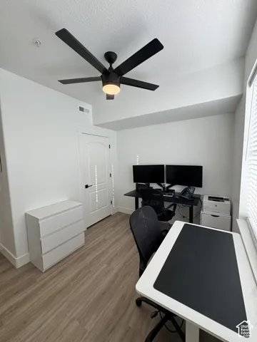 Wood-finish flooring, white walls, and a modern ceiling fan with integrated lighting