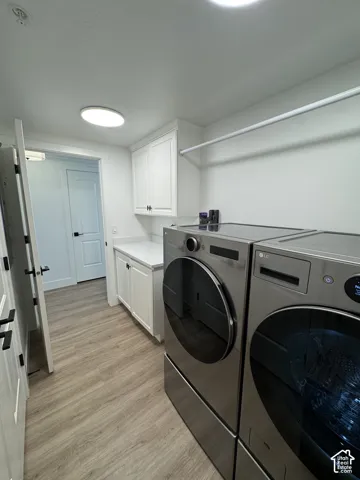 Wood-finish flooring, white cabinetry with dark hardware, built-in countertop, overhead storage cabinet, and an overhead lighting fixture