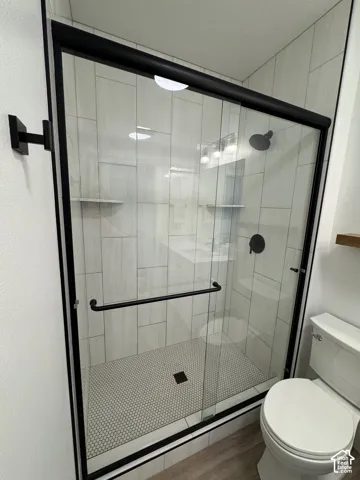 Glass-enclosed shower with matte black hardware, textured tile surround, and hexagonal floor tiles