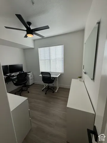 Wood-finish flooring, recessed lighting, ceiling fan, window with horizontal blinds, built-in wall-mounted whiteboard