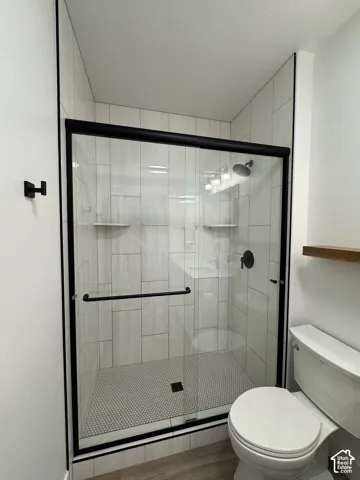 Walk-in shower featuring a sliding glass door with matte black frame, white subway tile surround, and hexagonal floor tile