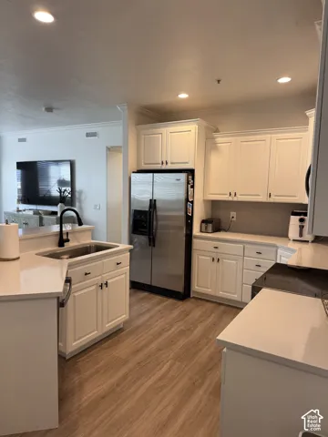 Kitchen featuring white shaker-style cabinetry, stainless steel appliances, light-toned countertops, wood-finish flooring, and recessed lighting