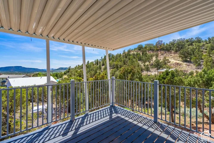 Spacious covered deck featuring a metal railing and composite decking