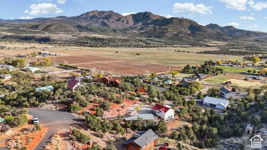 Expansive property with mountainous terrain, scattered residential structures, mature landscaping, and an unpaved road