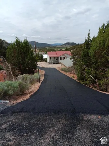 Paved driveway leading to a residence with a red roof, white siding, and an elevated porch