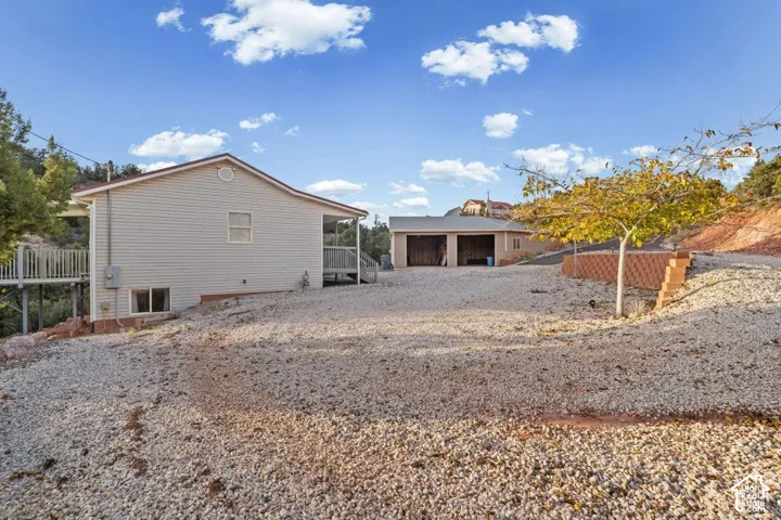 Exterior siding, two-car garage, terraced landscaping, and a side deck